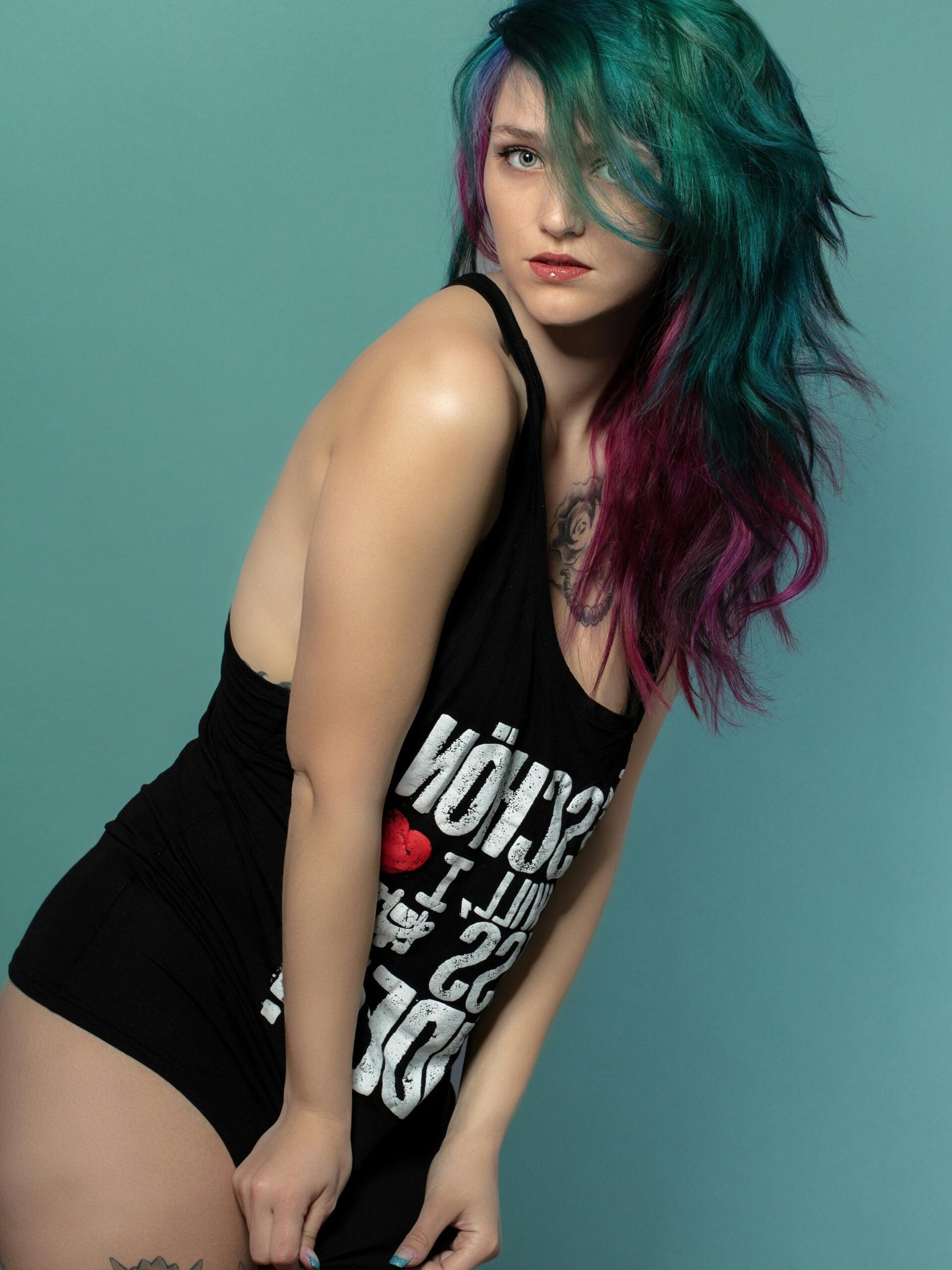 Vibrant fashion portrait of a woman with multi-colored hair against a turquoise background.