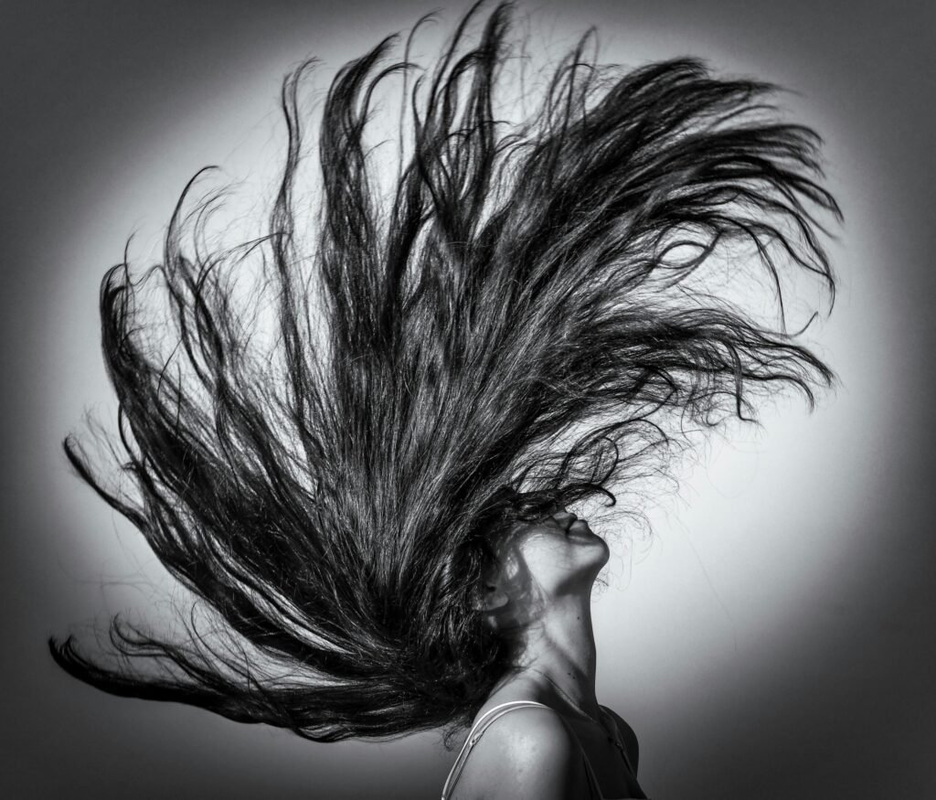 Black and white portrait of a woman flipping her hair dramatically.