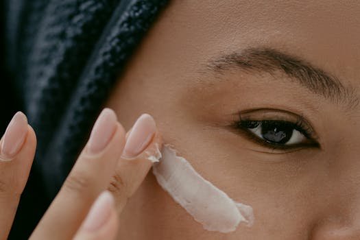 Extreme close-up of a woman applying cream to her cheek for healthy skin care. skincare