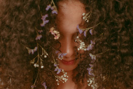 queda cabeloHeadshot of anonymous content female with small bright flowers with white and purple petals tangled in brown hair covering face