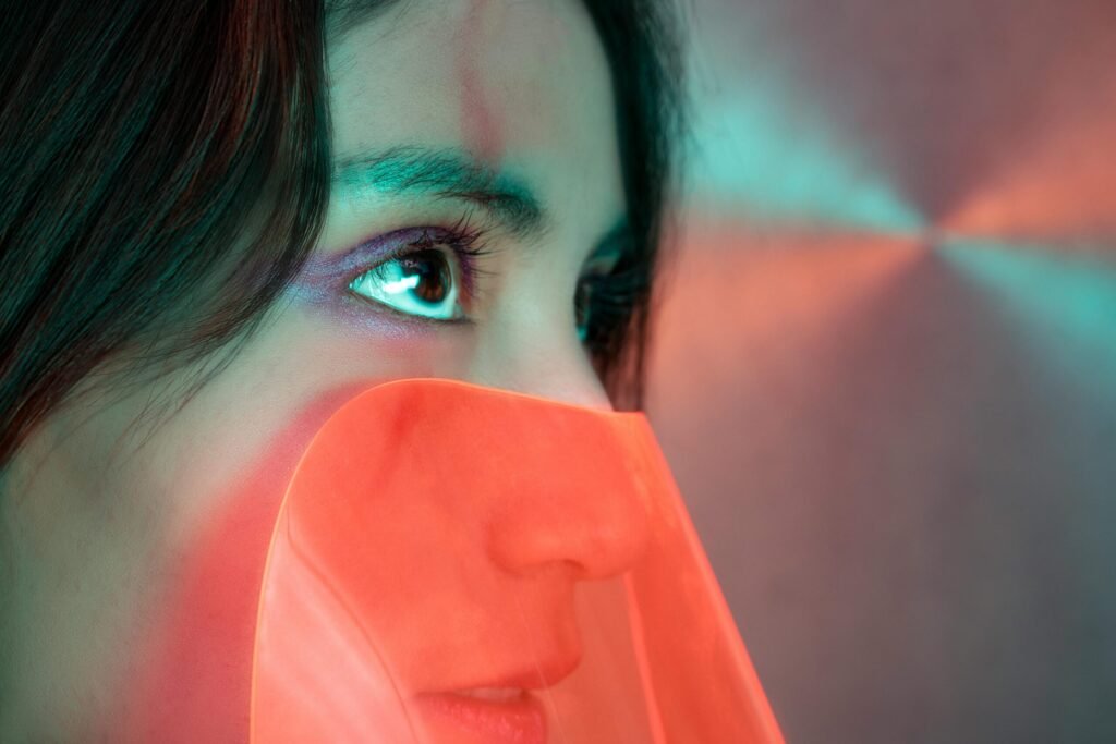 Close-up artistic portrait of a woman with vivid neon lighting and abstract elements.