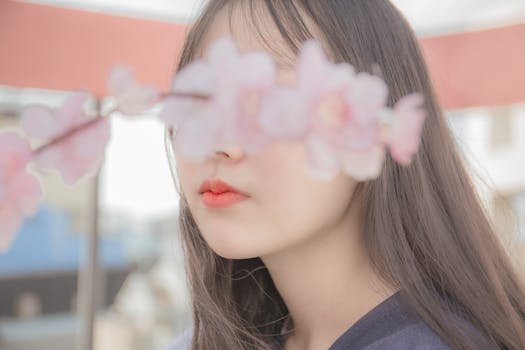 Elegant portrait featuring a soft focus on a young woman's face behind cherry blossoms, exuding serenity. dorama