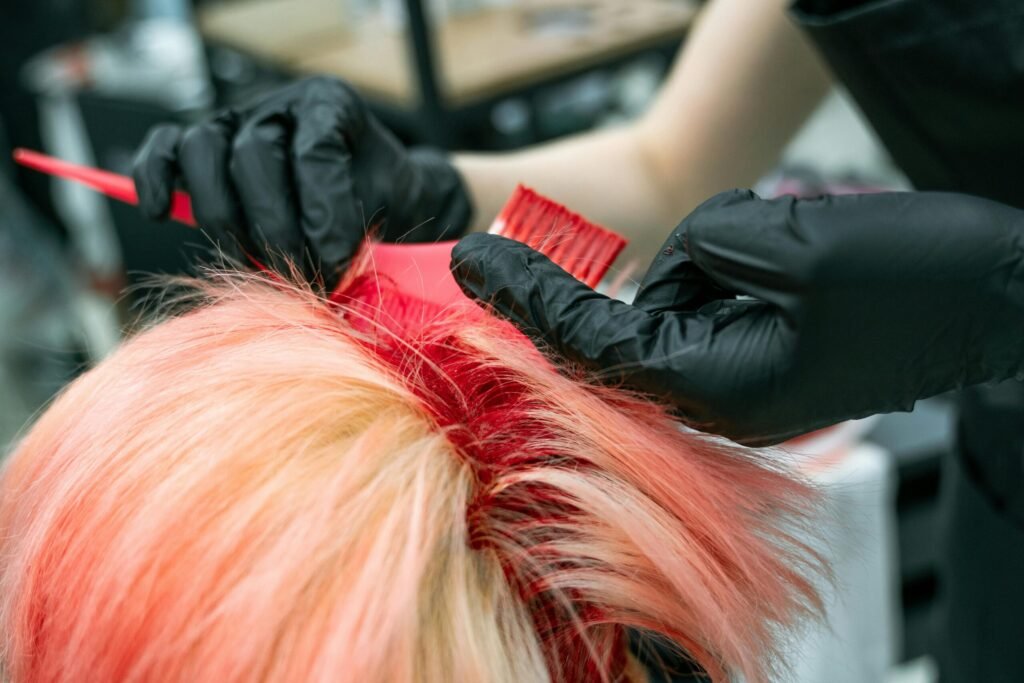 Close-up of vibrant hair coloring process with gloved hands applying dye.